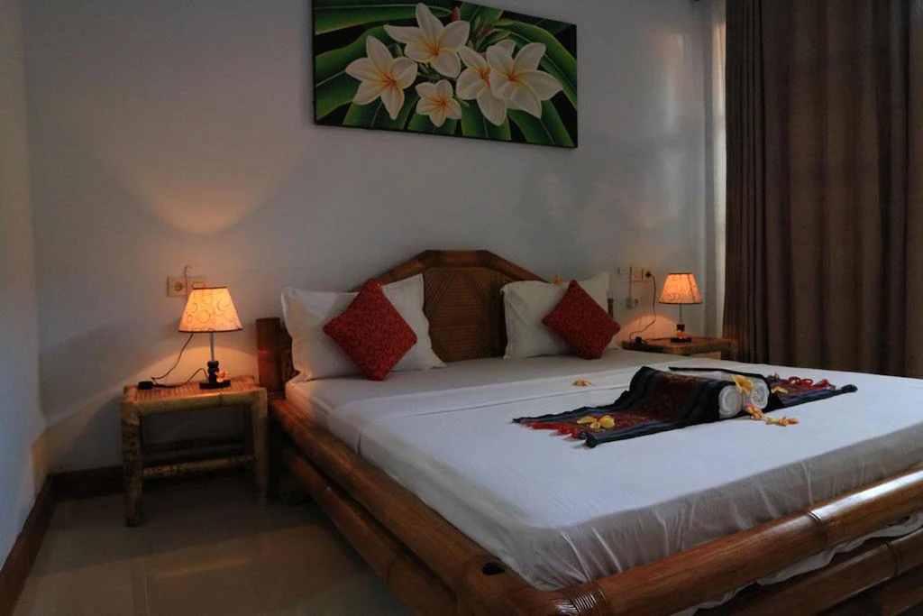 Standard Double bed with red pillows and frangipani art